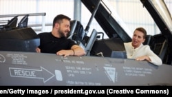 Președintele ucrainean, Volodimir Zelenski, și prim-ministra daneză, Mette Frederiksen, într-un avion de vânătoare de producție americană F-16 la baza aeriană Skrydstrup din Danemarca, pe 20 august 2023. 