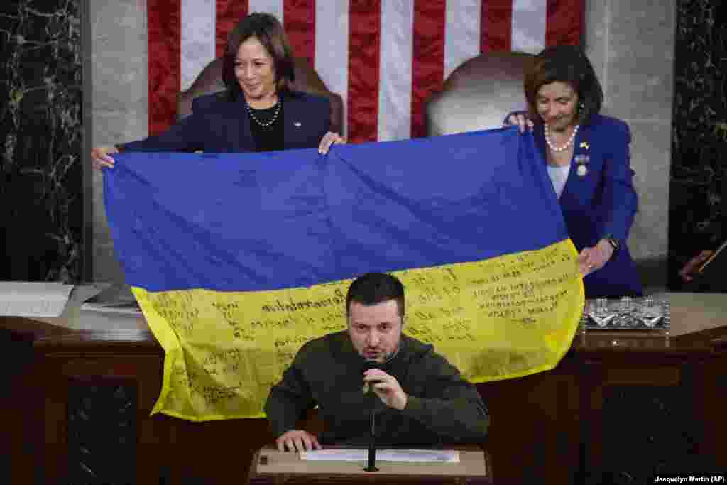 Вице-президент США Камала Харрис (слева) и спикер Палаты представителей Нэнси Пелоси реагируют на то, что президент Украины Владимир Зеленский вручает депутатам украинский флаг с автографами фронтовиков в Бахмуте во время выступления на совместном заседании Конгресса в Вашингтоне 21 декабря 2022 года. 