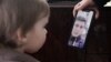 Ihar Losik's wife, Darya Losik, shows a photo of him to their young daughter in January 2023.