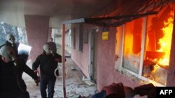 Pro-Russia protesters wearing gas masks storm a regional police building as one prepares a Molotov cocktail in Horlivka.