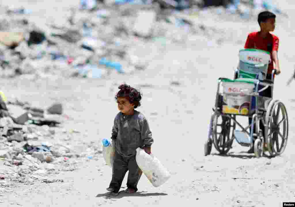 22 mai 2024 – O fetiță palestiniană cară două bidoane pentru a colecta apă, în Khan Younis, în sudul Fâșiei Gaza.În toamna anului 2025, o anchetă a Națiunilor Unite a stabilit că Israelul a comis genocid împotriva palestinienilor din Gaza. Guvernul israelian respinge cu vehemență aceste acuzații.